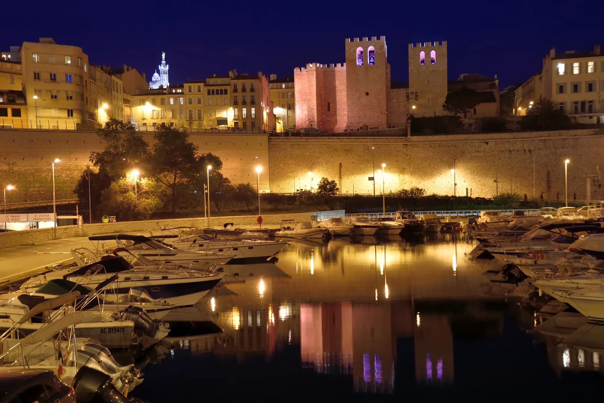 L'abbaye Saint-Victor éclairée la nuit, au-dessus des bateaux du Vieux-Port de Marseille