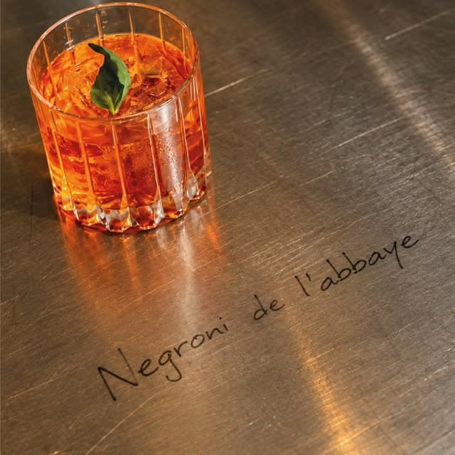 Negroni de l’Abbaye ambré, servi sur glaçons avec une feuille verte